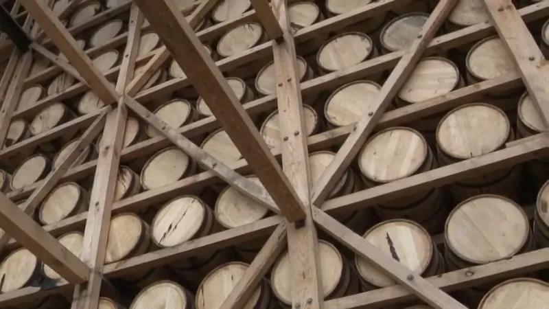Wooden racks packed with bourbon barrels aging inside a Kentucky warehouse