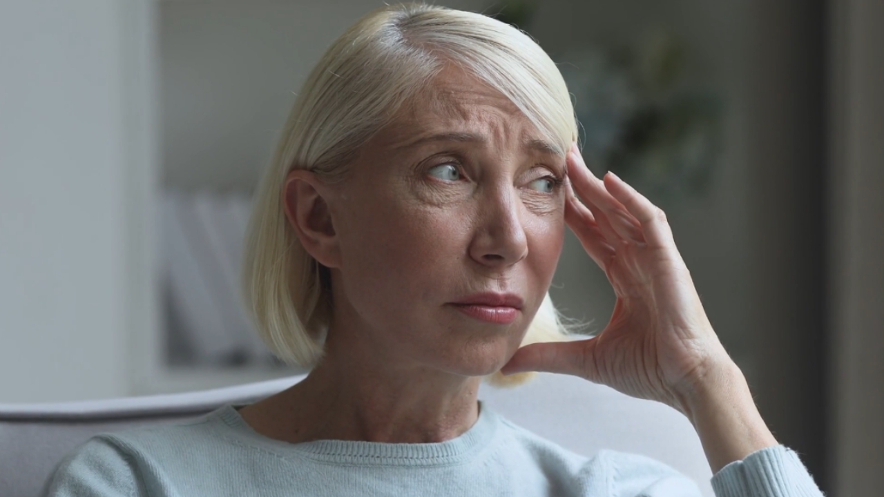 Woman over 50 sitting at home looking worried and stressed