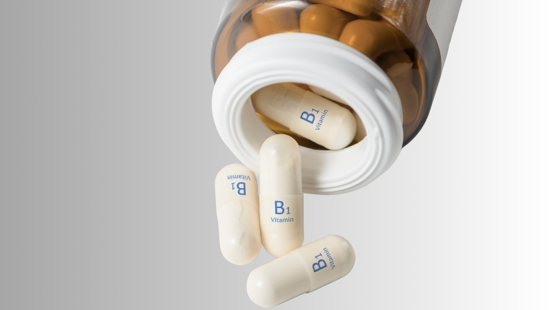 Open bottle with capsules labeled vitamin B1 spilling out, representing thiamine supplements