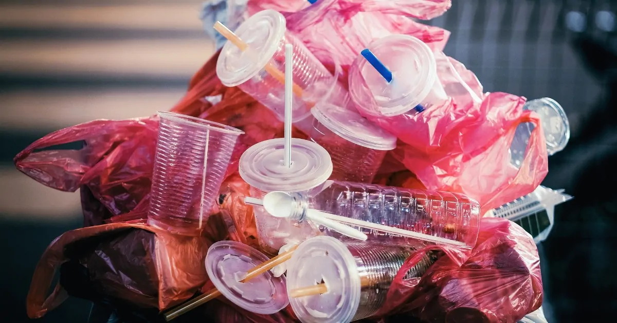 Pile of plastic trash with cups, bottles, and bags collected as combustible waste in an urban setting