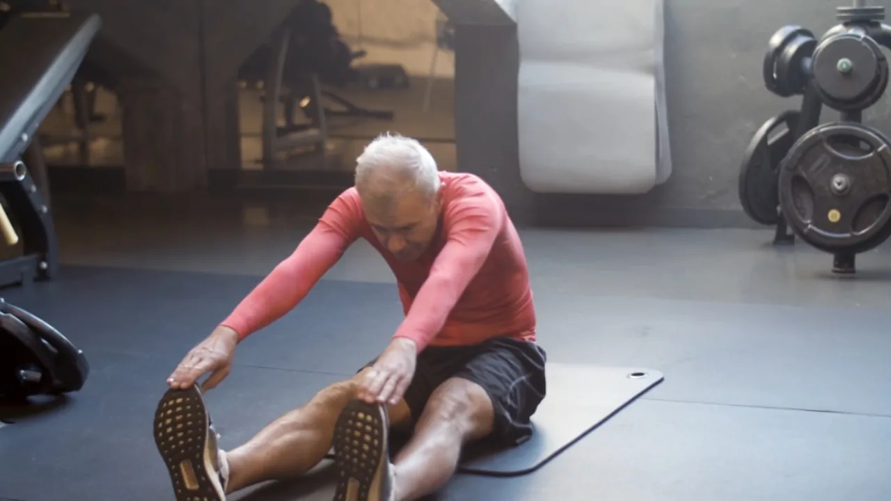 Older man stretching on a mat in a gym as part of exercise for osteoarthritis relief