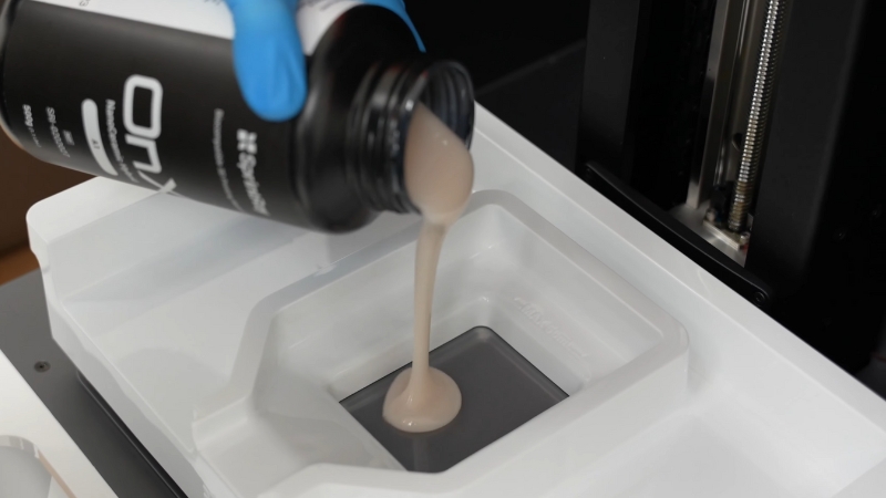 Dental ceramic resin being poured into a 3D printer vat for chairside crown fabrication