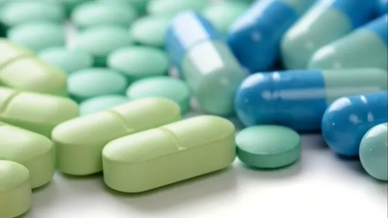 Close-up of green and blue painkiller tablets and capsules on a white surface