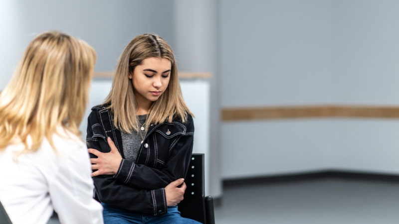Young woman sits with a counselor during a mental health support conversation