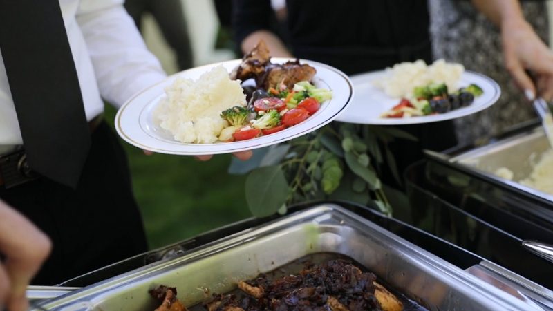 Food service workers plating meals at a catering or kitchen service station