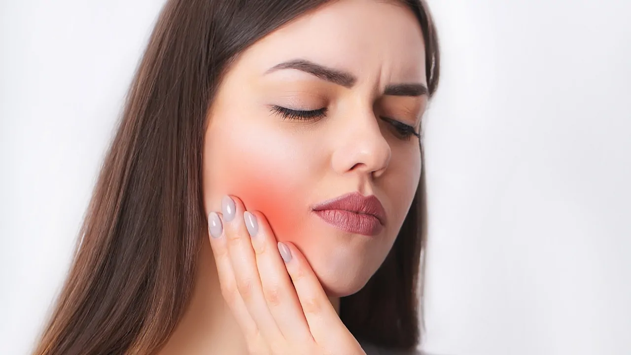 Woman holding her jaw in pain due to jaw joint disorder