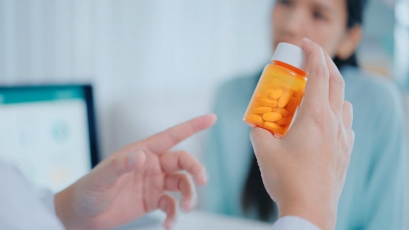 Doctor holding a pill bottle while discussing medication abortion with a patient