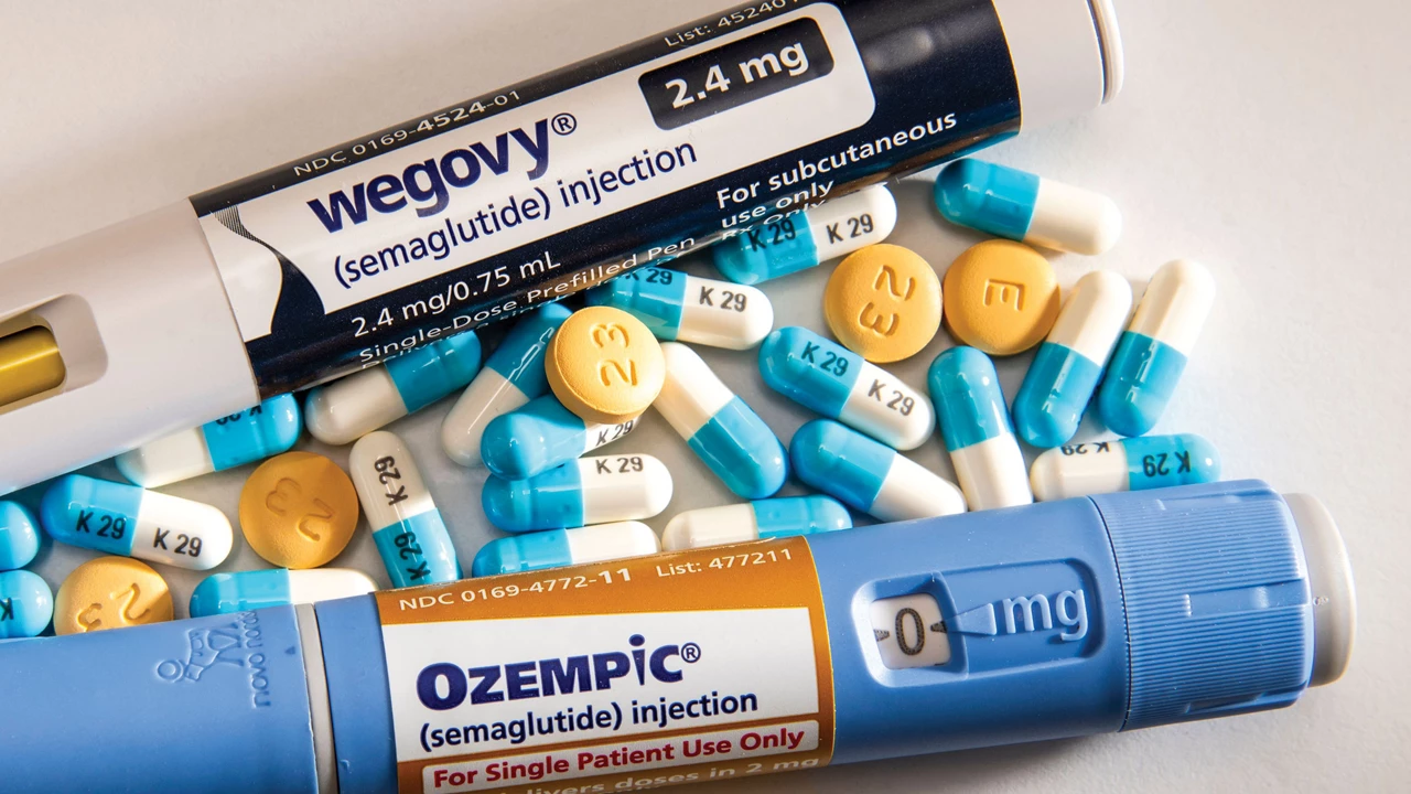 Wegovy and Ozempic semaglutide injection pens placed among assorted prescription pills and capsules on a white surface.