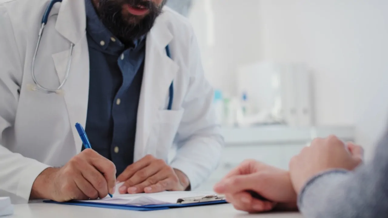 Doctor reviewing paperwork with a patient during PECOS enrollment process in a medical office