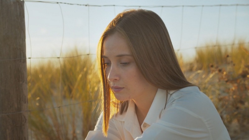 Young woman sits alone outdoors with a pensive expression, reflecting emotional distress in young adults