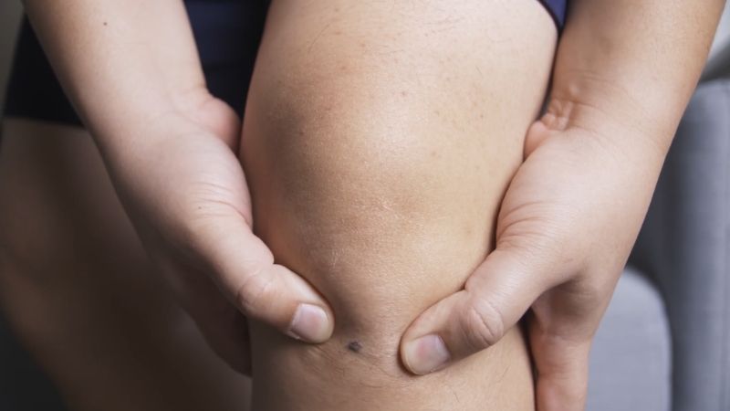 Person holding their knee, showing joint pain linked to osteoarthritis