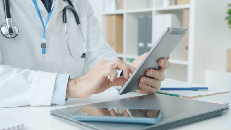 Healthcare provider reviewing information on a tablet during PECOS enrollment data review