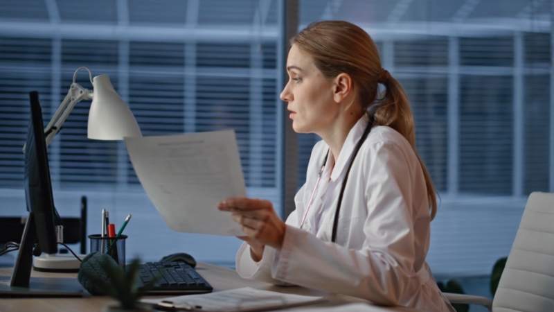 Healthcare professional reviewing documents at a desk during PECOS enrollment access setup