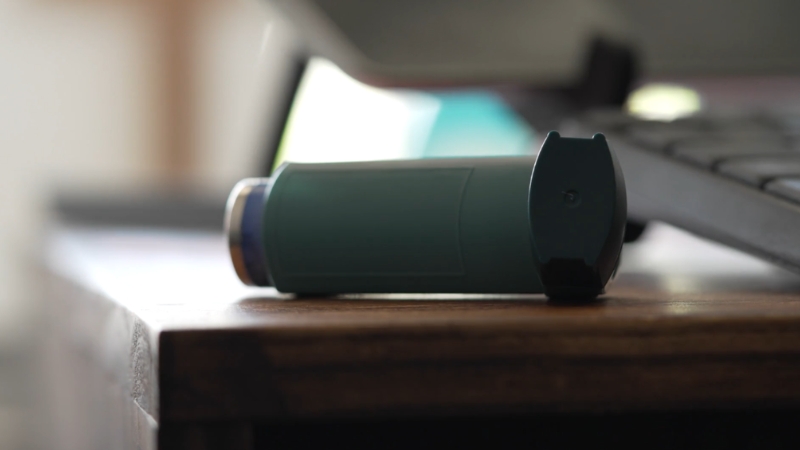 Asthma inhaler resting on a wooden table indoors