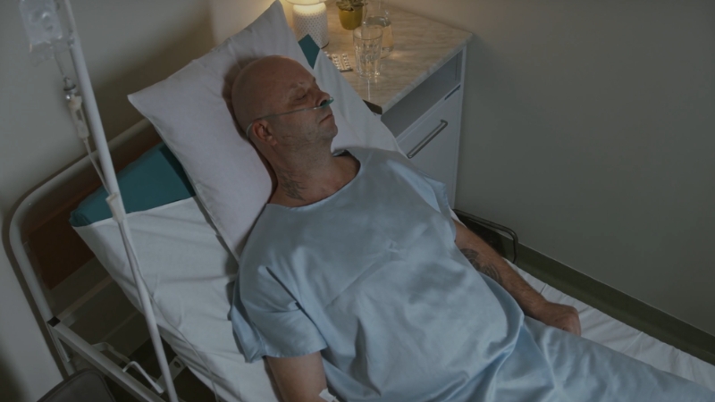 Man lying in a hospital bed with oxygen support