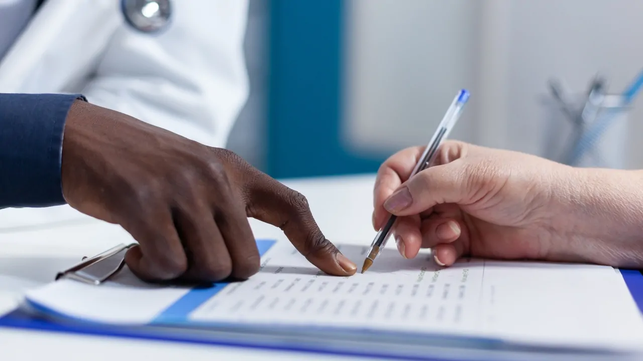 Doctor and patient review paperwork related to hospital discharge rates during hospital discharge process