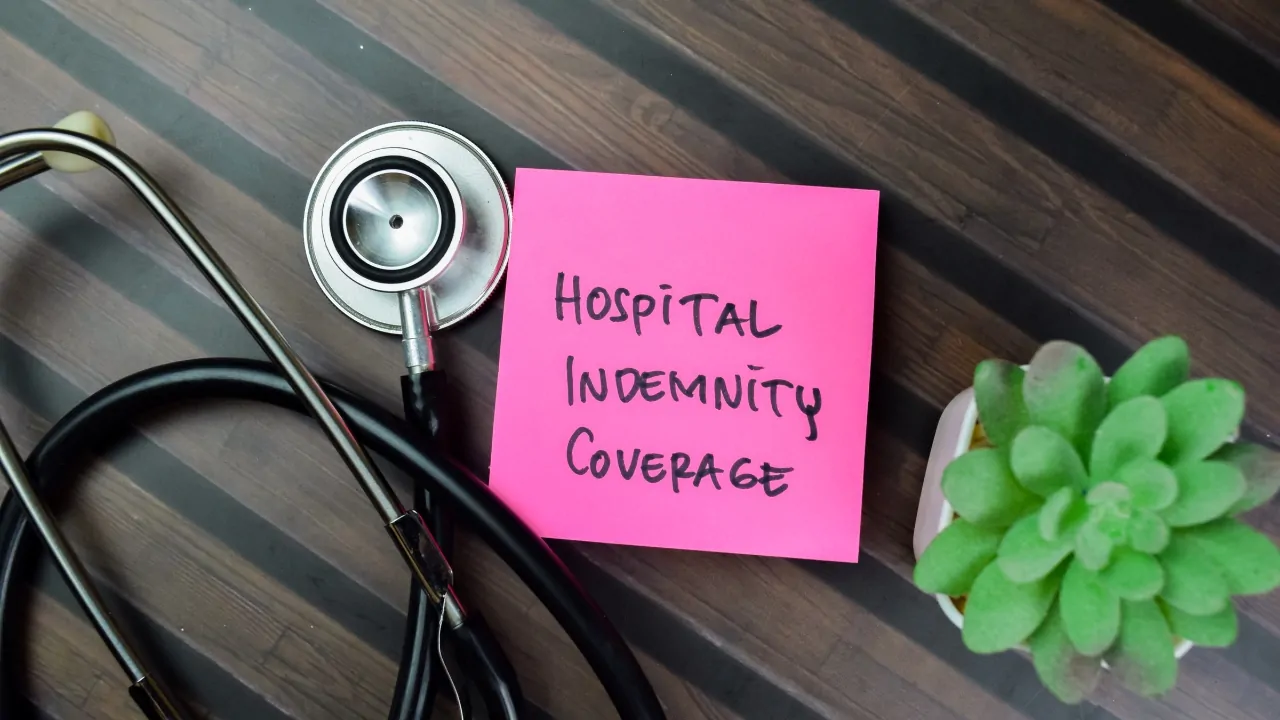 Note labeled hospital indemnity insurance coverage next to a stethoscope on a desk