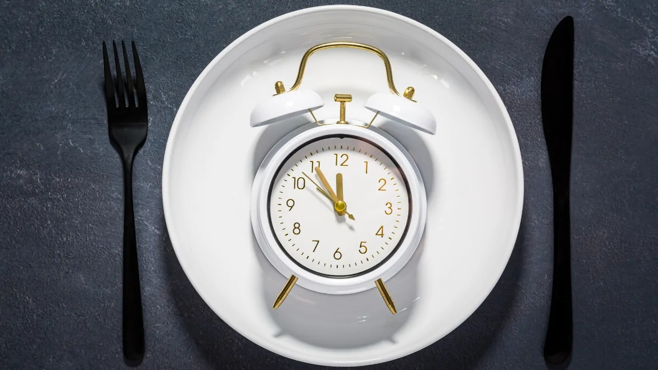 Illustration of how autophagy works with a clock placed on a plate between a fork and knife