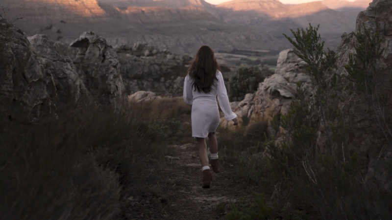 Woman walking through a quiet natural landscape showing the calming effect of natural environments on mental well-being