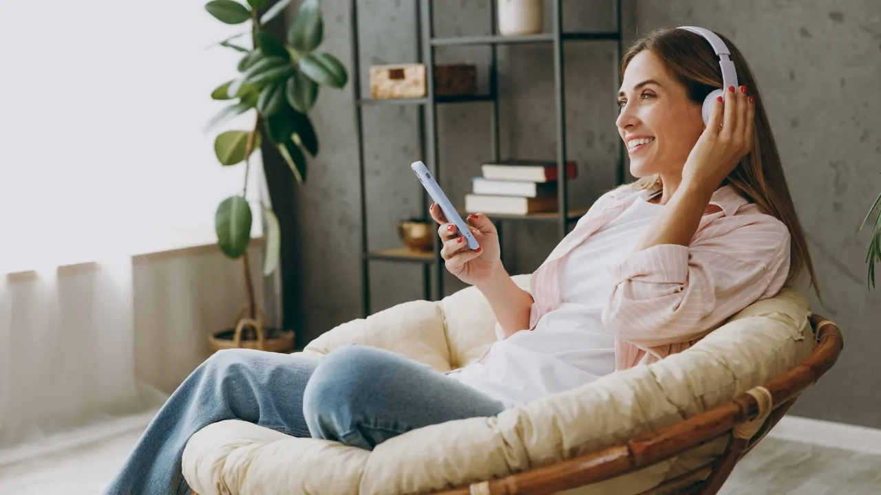 Woman relaxing at home with headphones, listening to music on her phone