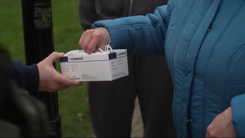 Person hands out face masks during meningitis outbreak response in Kent