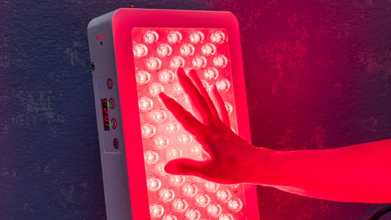 Hand placed in front of a near infrared light therapy panel during a session