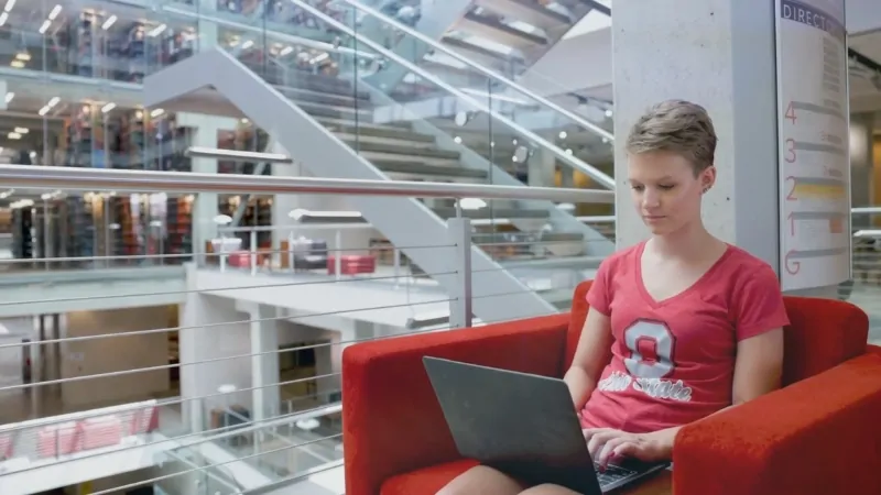 Ohio State University student using a laptop inside a modern campus library
