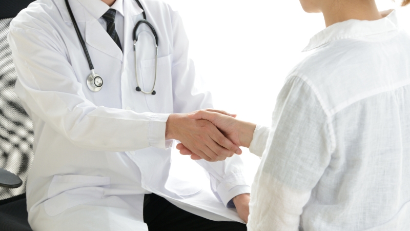 Doctor shakes hands with a patient during hospital discharge after treatment