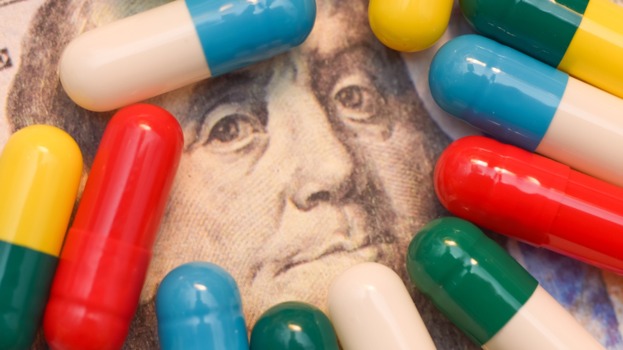 Colorful pills placed over a dollar bill, representing rising US healthcare spending costs