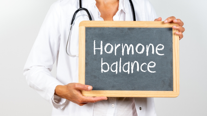Doctor holding a chalkboard with the words hormone balance written on it
