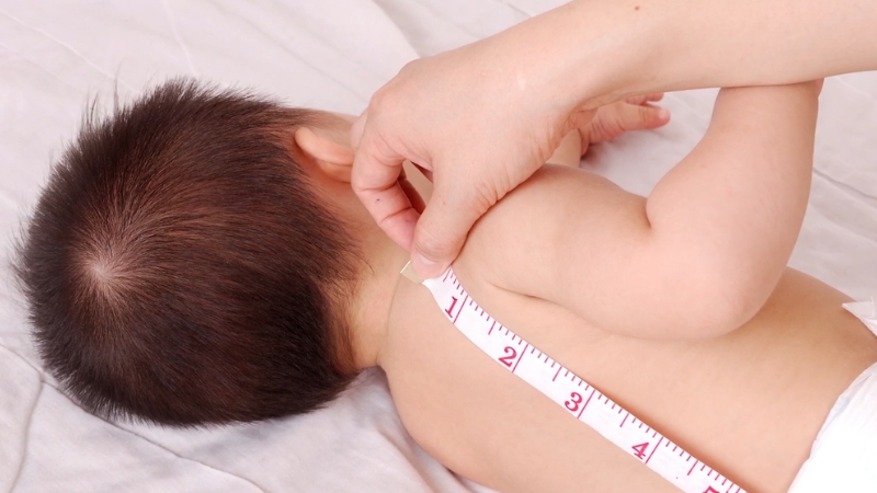 Baby with a measuring tape across the back during a growth check