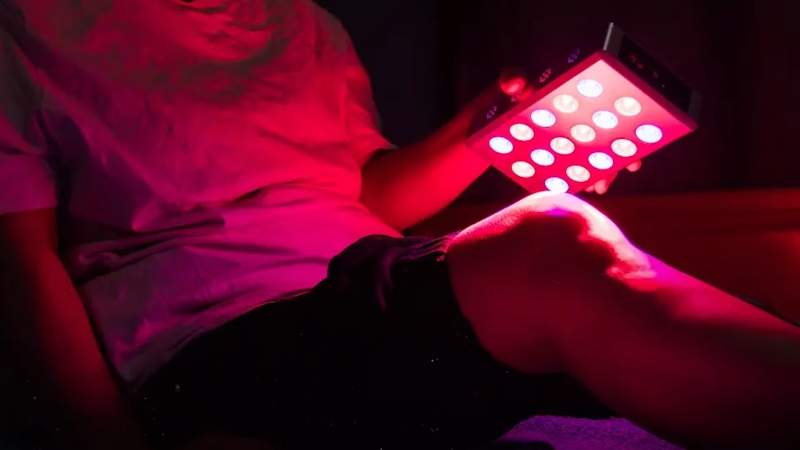 Person using a handheld near infrared therapy device on their knee at home