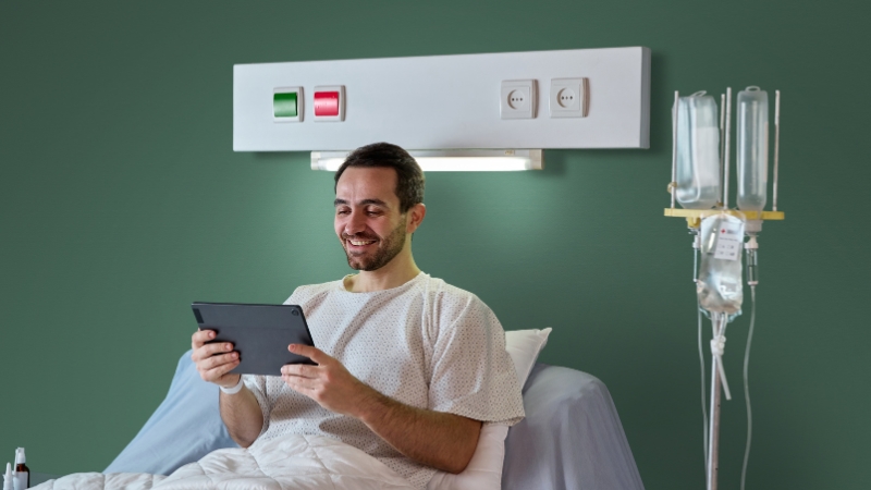 Patient in a hospital bed using a tablet during recovery
