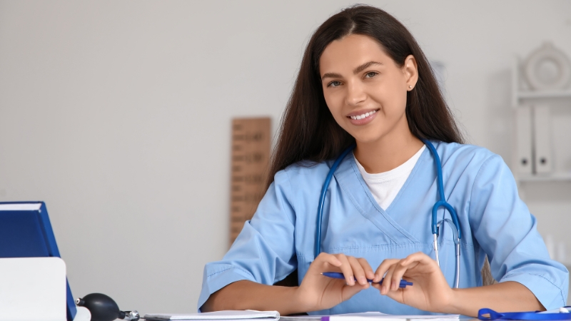 Nursing student in scrubs studying for the NCLEX-RN exam at a desk