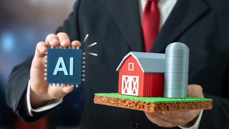 Person holds an AI chip next to a small farm model with a barn and silo