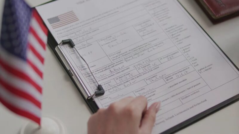 Person reviewing a visa application form next to a small US flag