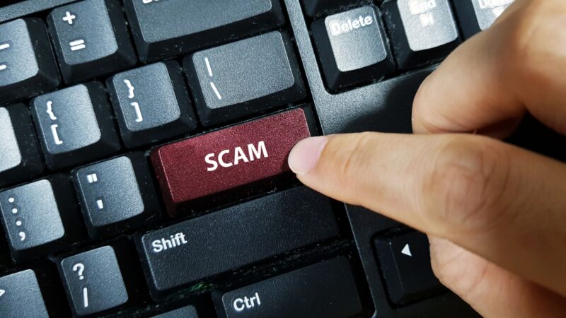 Finger pressing scam key on keyboard to show government scam warning signs