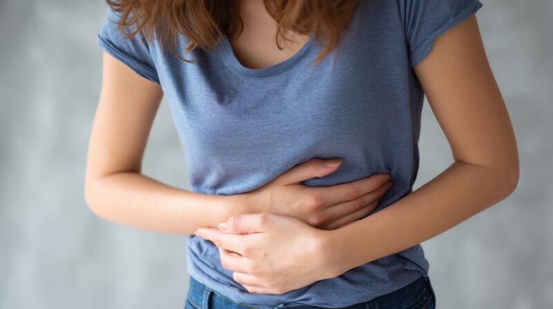 Person holding their abdomen, indicating stomach pain or digestive discomfort