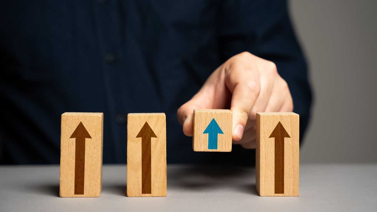 A person arranges wooden blocks with arrows to show different levels of progress
