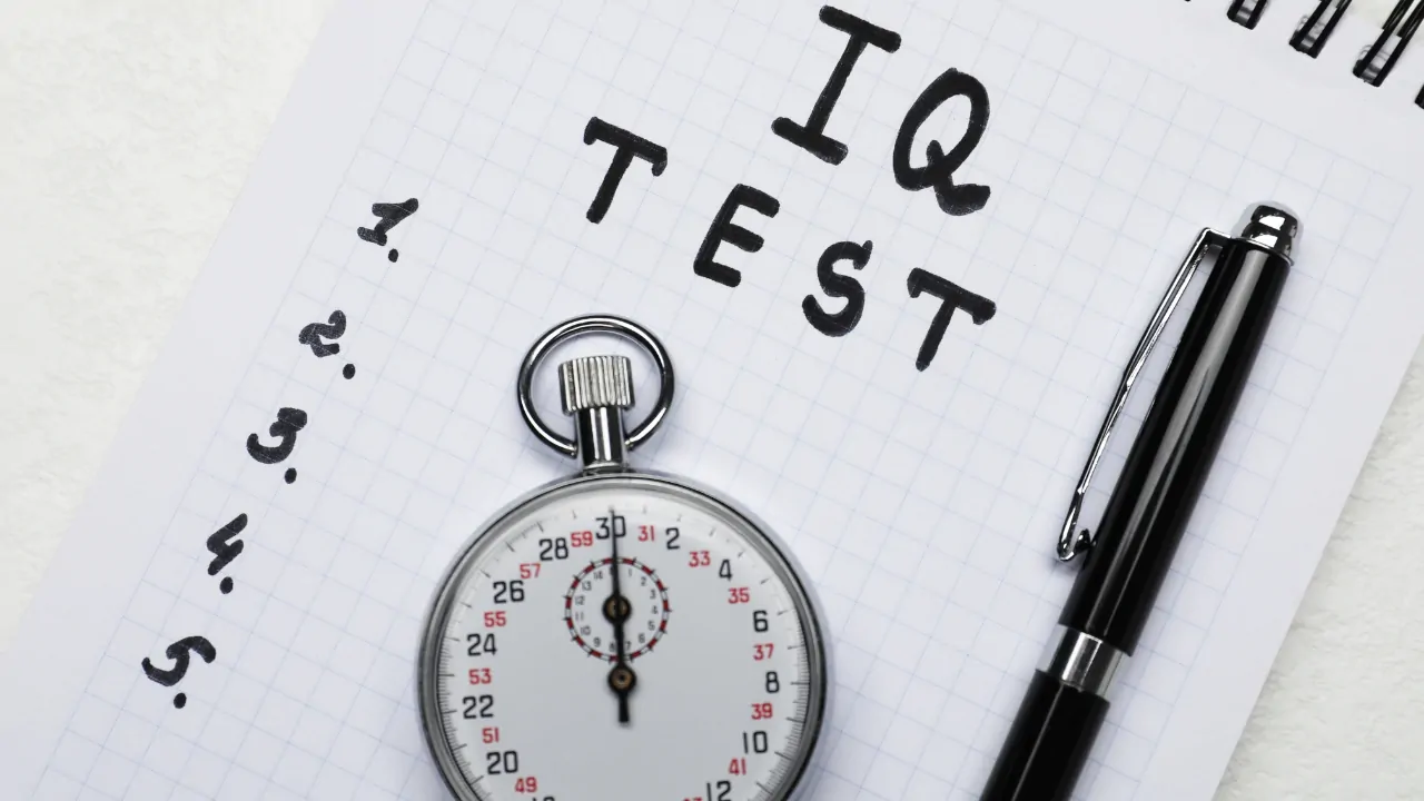 A stopwatch and pen sit on an IQ test sheet with numbered questions