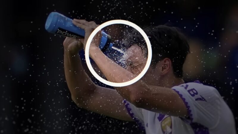 Football player cools his face with water during a match in extreme heat