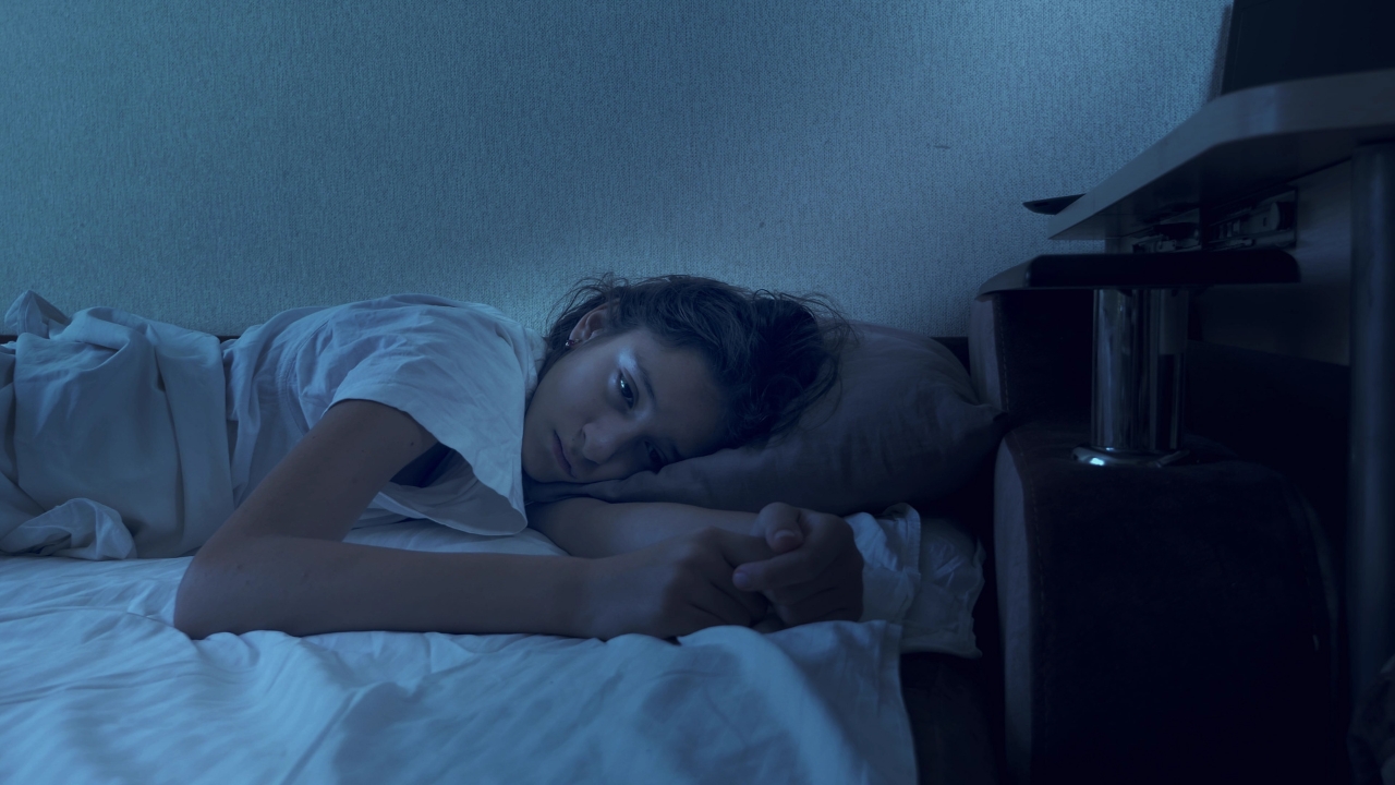 Teen lies awake in bed at night after poor sleep