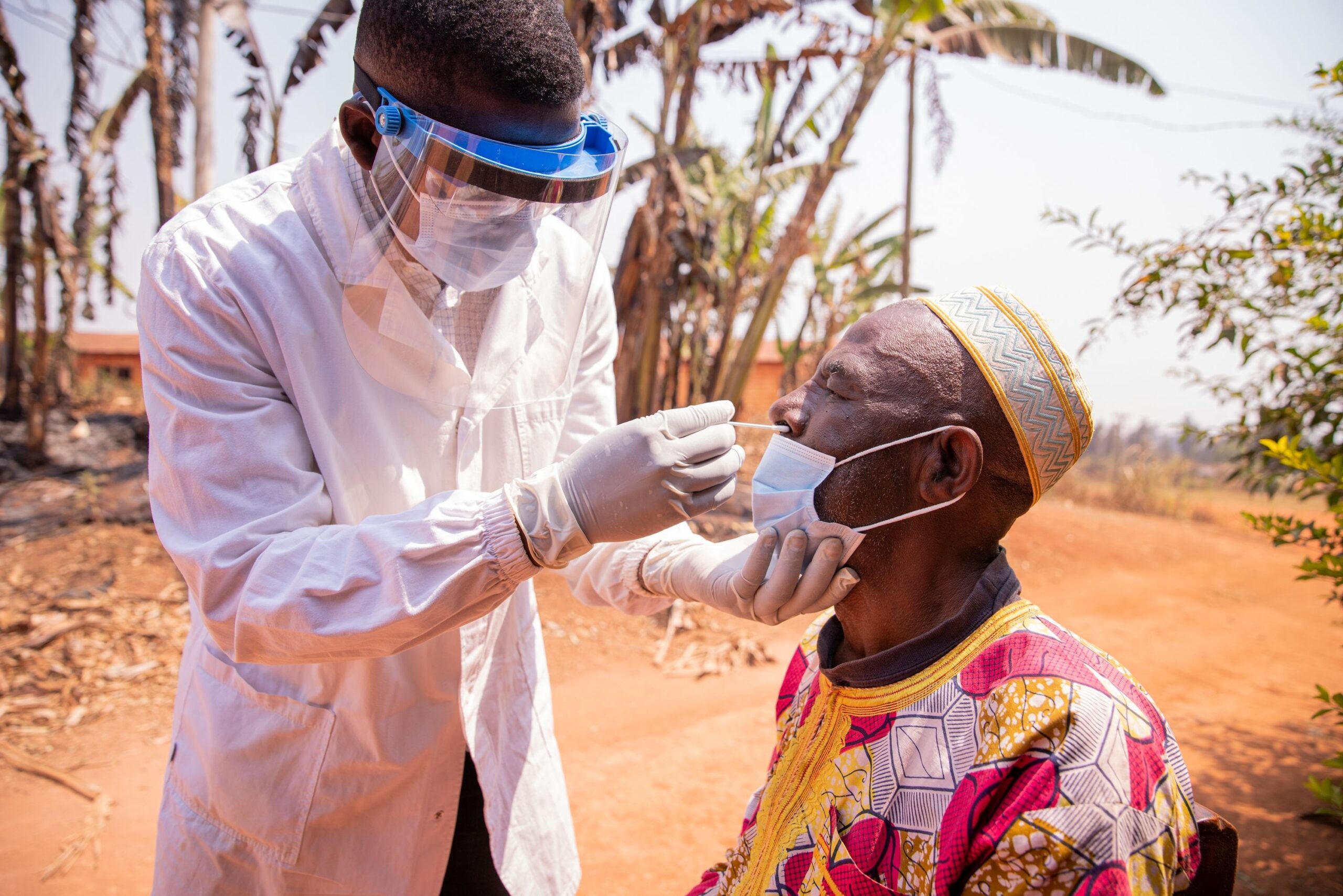 An African doctor performs a nasal swab test on an elderly patient.