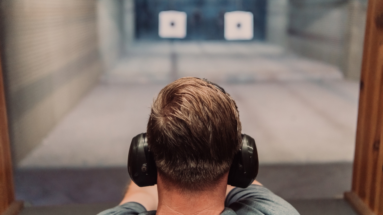 A young man wears hearing protection at an indoor gun range in the US