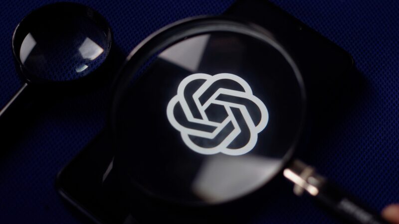 Magnifying glass over the OpenAI logo on a smartphone screen