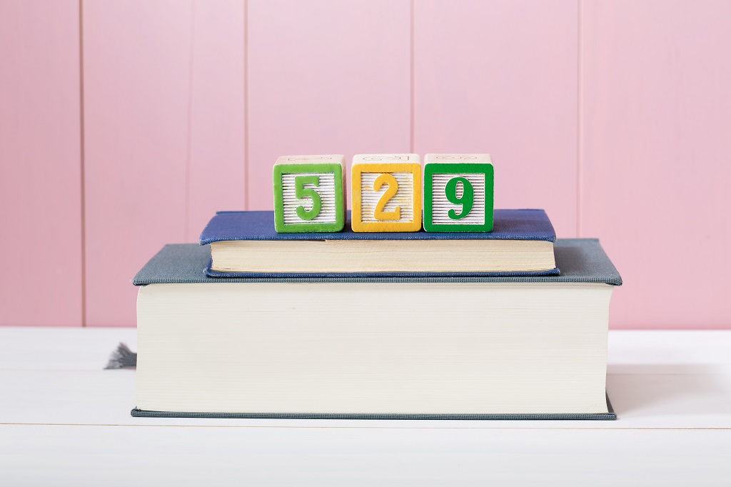 Stack of books with colorful number blocks spelling 529, representing a 529 college savings plan and education-focused investing