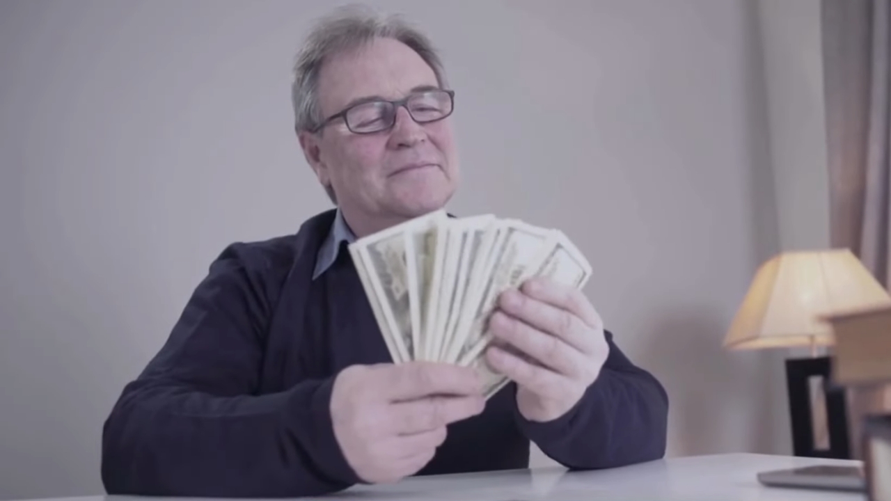 An older man counts cash at a table during a healthcare cost review