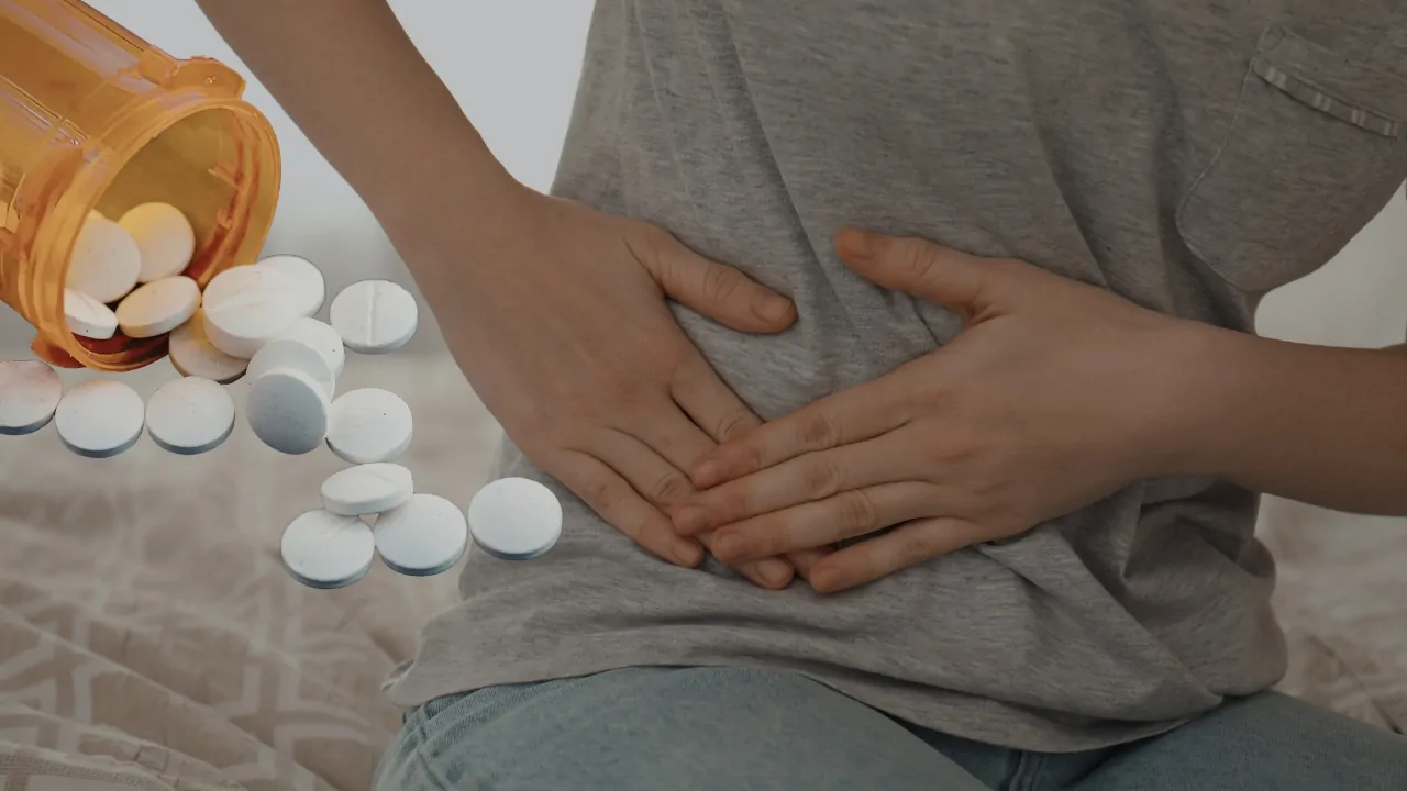 Person holding their abdomen with spilled pills nearby, representing KRAS-targeting drug treatment for pancreatic cancer