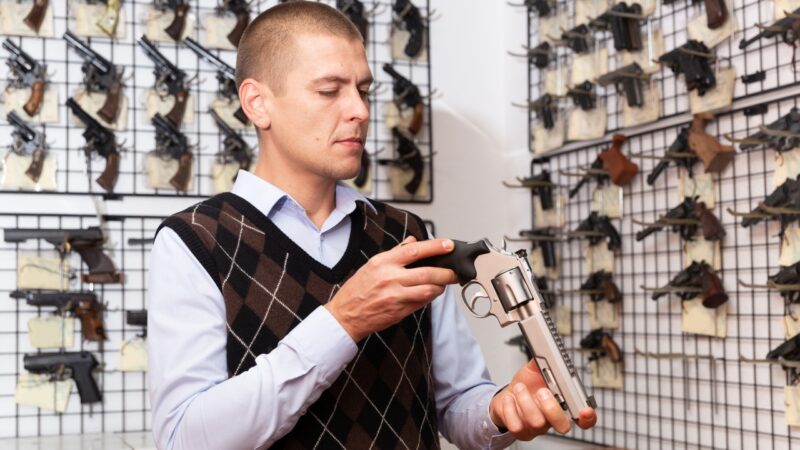 Man examining a handgun inside a gun store