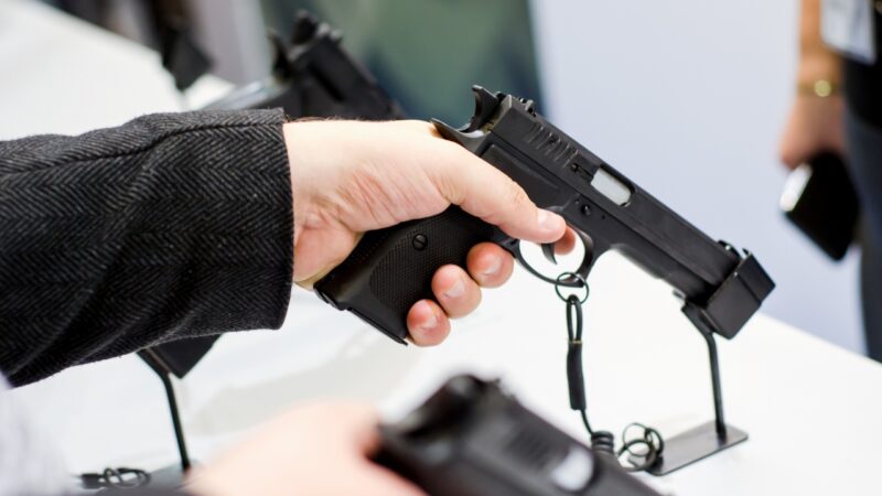 Person holding a handgun during a firearm store background check process